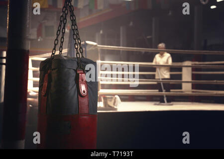 a sandbag hanging in front of a boxing ring have a janitor was cleaning Stock Photo