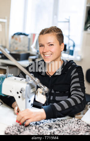 Seamstress sewing at machine, portrait. Female tailor stitching material at workplace. Preparing fabric for clothes making. Tailoring, garment industr Stock Photo