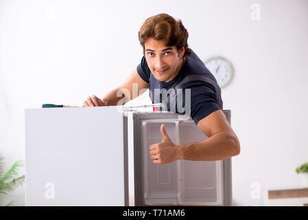 Young handsome contractor repairing fridge Stock Photo