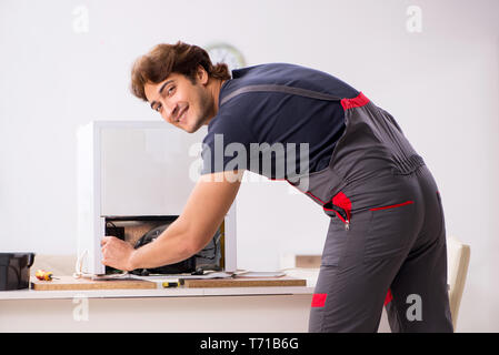 Young handsome contractor repairing fridge Stock Photo