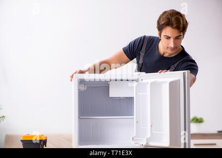Young handsome contractor repairing fridge Stock Photo