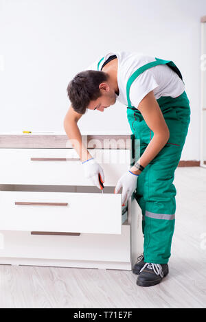 Young worker with cupboard in home renovation concept Stock Photo