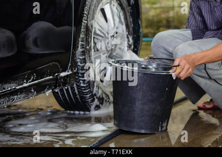 Clean the car wheels with car wash foam and black water tank. Stock Photo