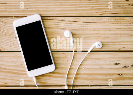 Blank screen smartphone with earphone on wooden table Stock Photo