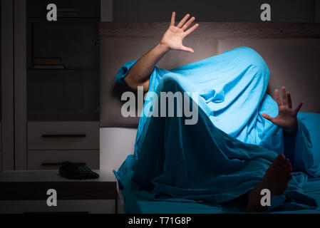 Young man scared in his bed having nightmares Stock Photo