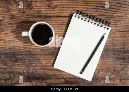 Open blank notebook, pencil and coffee on a dark wood background. Flat lay with copy space. Stock Photo