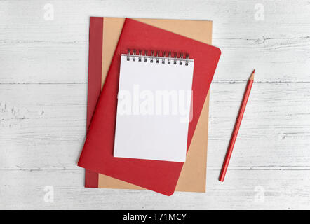 Stack of notebooks and a red pencil on a white wood background. Flat lay with copy space Stock Photo