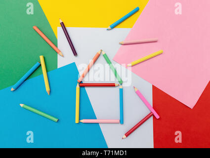 Colored pencils in the shape of a house on colored paper. Stock Photo
