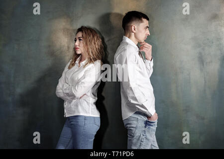 Young couple in love man and woman are offended at each other and no one wants to put up, they are standing with their backs to each other against the wall, toned Stock Photo