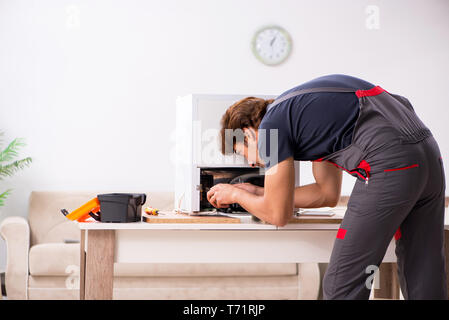 Young handsome contractor repairing fridge Stock Photo