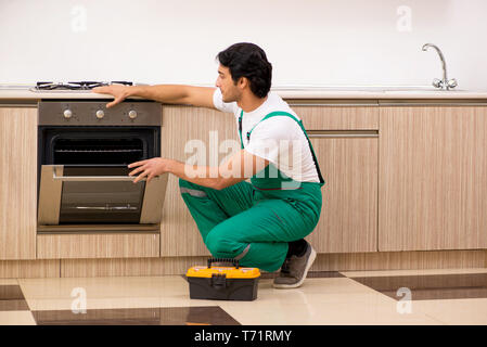 Young contractor repairing oven in kitchen Stock Photo