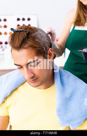 Woman hairdresser applying dye to man hair Stock Photo