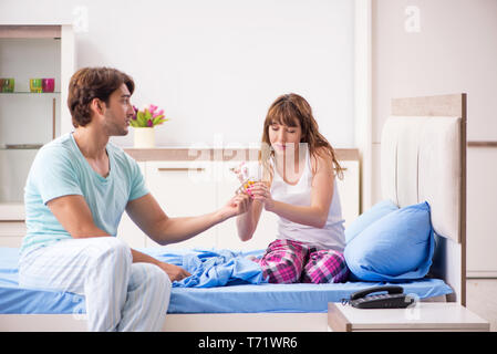 Young husband looking after sick wife in the bedroom Stock Photo