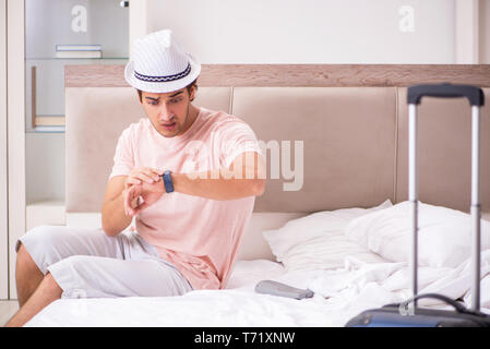 Man with suitcase in bedroom waiting for trip Stock Photo