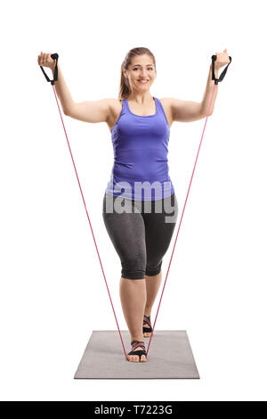 Full length portrait of a young woman exercising with a stretching band isolated on white background Stock Photo