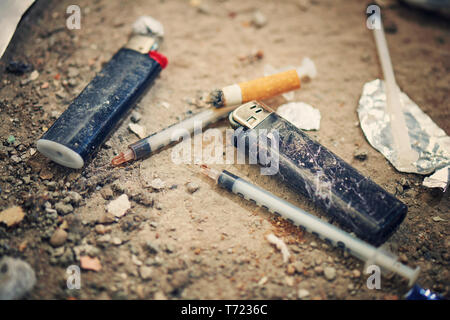 Used syringe on the ground - drugs Addiction equipment. Heroin, syringe, cigarette and lighter - drug addiction concept Stock Photo