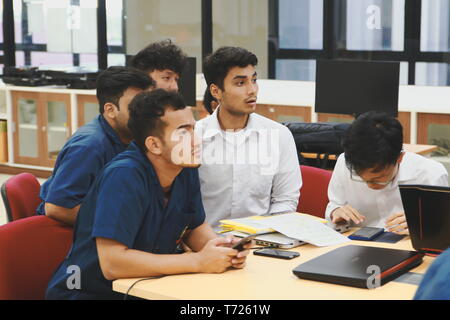 Groups of Thai Computer Engineering students at Assumption University (ABAC) Working on their coding project in a classroom Stock Photo
