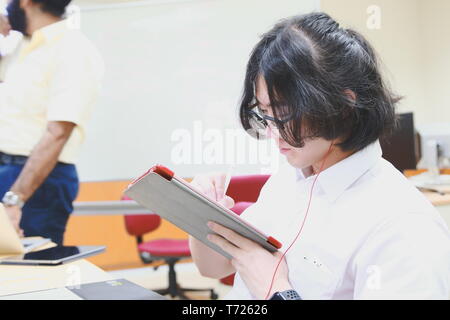 Chinese Computer Engineering Student taking lecture note on his iPad using Apple Pencil during a class Stock Photo