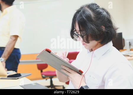 Chinese Computer Engineering Student taking lecture note on his iPad using Apple Pencil during a class Stock Photo