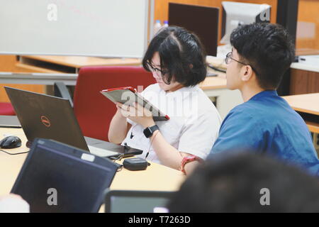 Chinese Computer Engineering Student taking lecture note on his iPad using Apple Pencil during a computer programming class Stock Photo