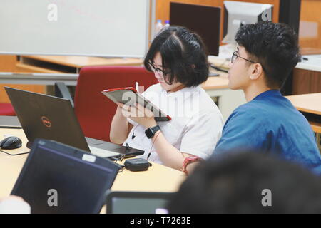 Chinese Computer Engineering Student taking lecture note on his iPad using Apple Pencil during a computer programming class Stock Photo