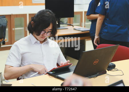 Chinese Computer Engineering Student taking lecture note on his iPad using Apple Pencil during a computer programming class Stock Photo