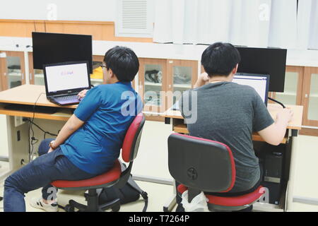 Two Thai Computer Engineering students at Assumption University (ABAC) working on their own laptop during class Stock Photo