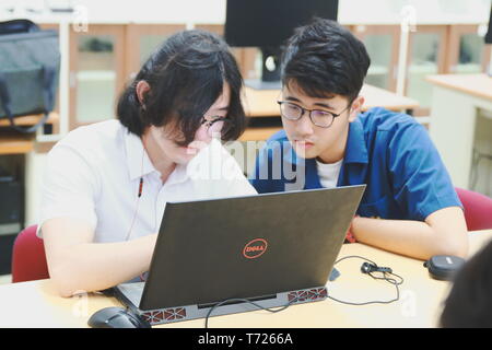 Two Chinese computer engineering student working together on a laptop in a computer programming class Stock Photo