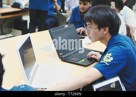 Portrait of a Computer Engineering student at Assumption University working on his coding project on two laptops Stock Photo
