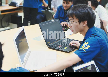 Portrait of a Computer Engineering student at Assumption University working on his coding project on two laptops Stock Photo