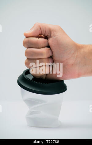 closeup of a man smashing a white plastic cup, covered with a black lid, on a white background Stock Photo