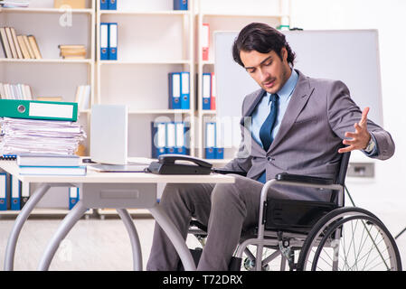 Young handsome employee in wheelchair at the office Stock Photo