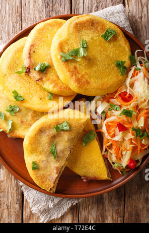 Traditional Latin American pupusas served with curtido closeup on a plate on the table. Vertical top view from above