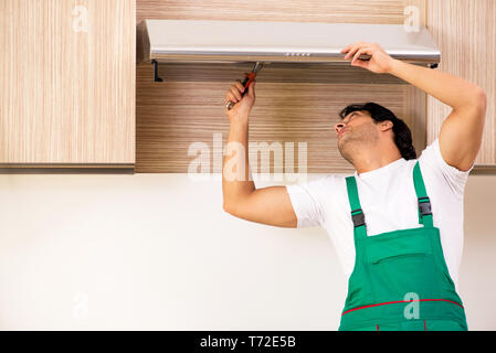 Young contractor repairing air-conditioner in kitchen Stock Photo