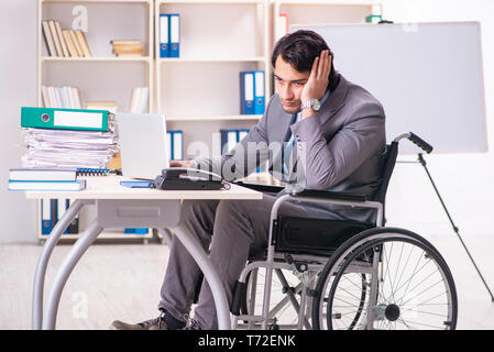 Young handsome employee in wheelchair at the office Stock Photo