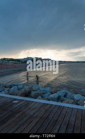 People in the sea under a stormy sky Stock Photo
