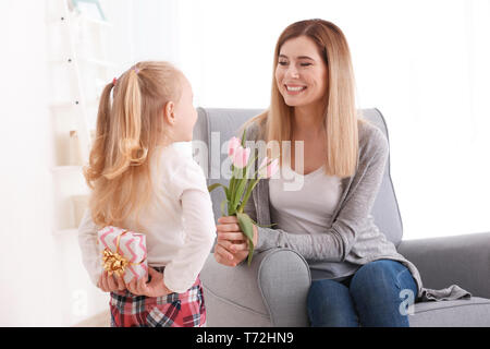 Cute little girl hiding gift box for mother behind her back Stock Photo