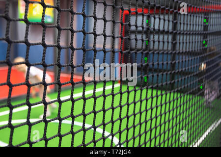 Blurred children are playing behind the net at indoor playground in activity park. Stock Photo