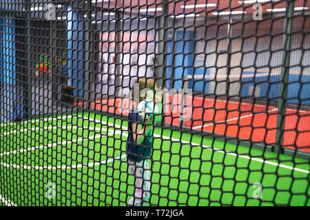 Blurred children are playing behind the net at indoor playground in activity park. Stock Photo