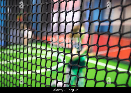 Blurred children are playing behind the net at indoor playground in activity park. Stock Photo