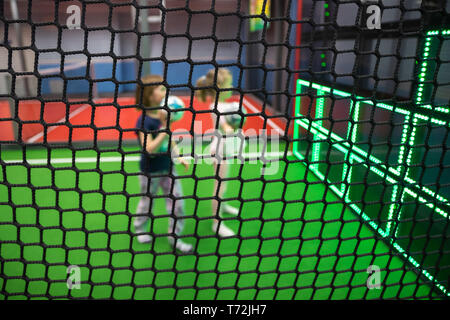 Blurred children are playing behind the net at indoor playground in activity park. Stock Photo