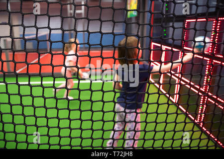 Blurred children are playing behind the net at indoor playground in activity park. Stock Photo