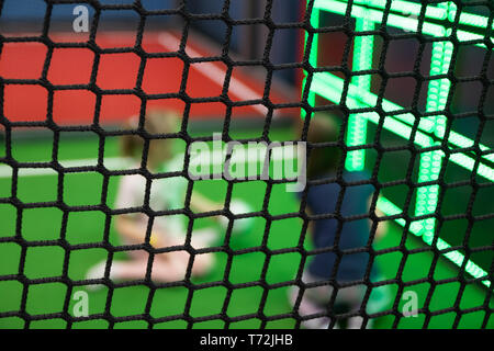 Blurred children are playing behind the net at indoor playground in activity park. Stock Photo