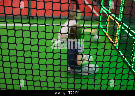 Blurred children are playing behind the net at indoor playground in activity park. Stock Photo