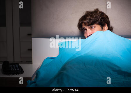 Young man scared in his bed having nightmares Stock Photo