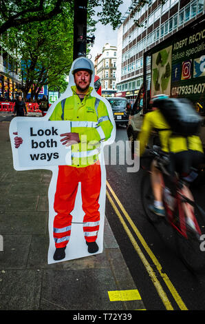 Road Safety Sign - unusual sign telling pedestrians to look both ways in London's Tottenham Court Road as it changes from one way to two way traffic. Stock Photo