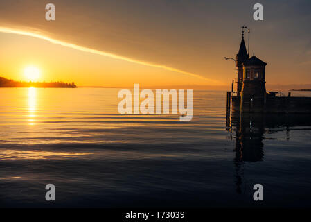 Early morning on the lake Constance and a small lighthouse. Sunrise reflected in water lake in Konstanz, Germany. Relaxing landscape. Stock Photo