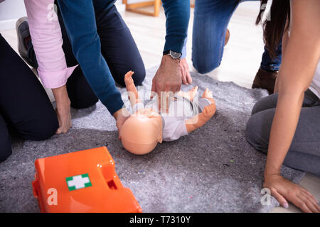 Specialist Giving Baby CPR Dummy First Aid Training To His Colleagues Stock Photo