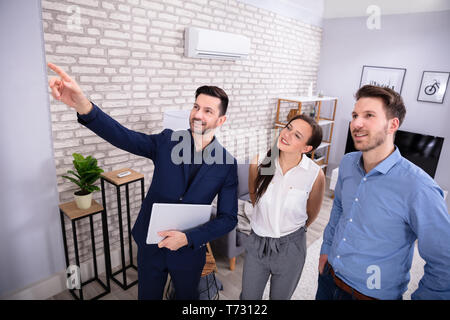 Male Real Estate Agent Pointing New House To Young Couple