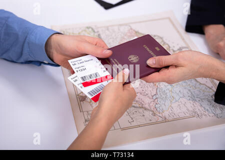 Close-up Of Human's Hand Holding Passport And Boarding Pass In Office Stock Photo